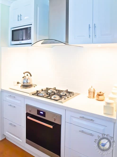Close-up of a white kitchen cook zone with a gas cooktop, built-in oven and rangehood, High Wycombe job