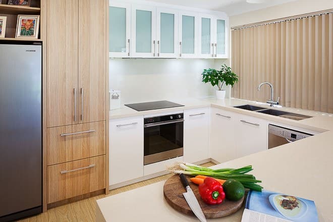 Light-oak and white kitchen cabinetry with stone benchtops and integrated appliances