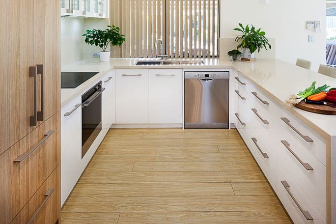 Light-oak U-shaped kitchen with an integrated dishwasher, stone benchtops and a sink under the window
